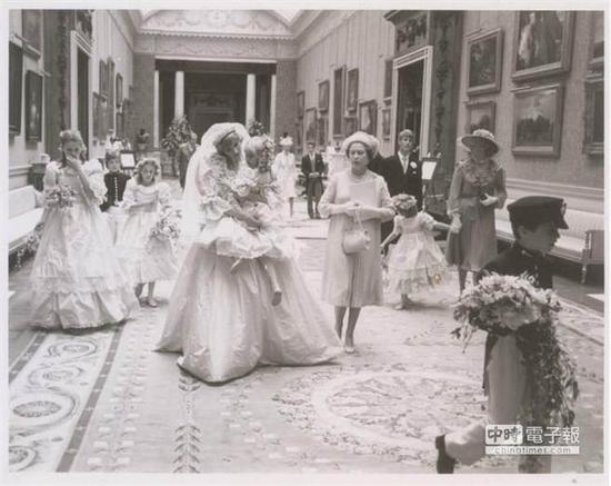 黛安娜王妃穿著美麗的婚紗，抱起小花童，笑容可掬十分親切。 (圖片取自me​​tro)