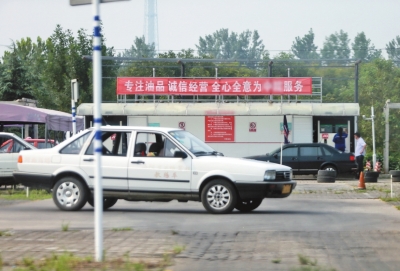 學員正在練車，后面的加油站正在給一輛車加油。