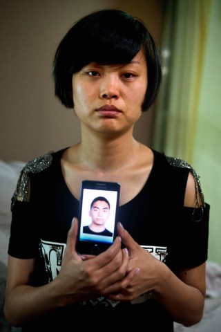 天津港消防支队五大队失联队员李长兴的姐姐李延晓手持弟弟的照片