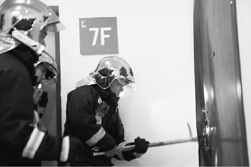 消防队员对着火的居民家进行破门