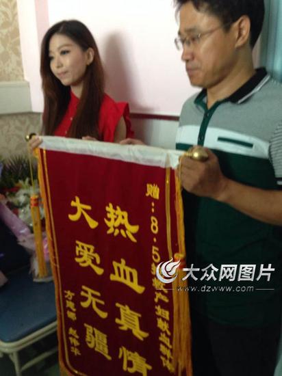 产妇一家向献血者赠送锦旗,图为献血者接受锦旗。