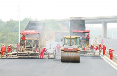 在西環路高新區段施工現場，工人正在鋪瀝青。