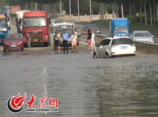 世纪大道凤鸣路口积水严重,一辆白色轿车抛锚。