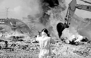 　　8月23日，武警交通部队战士用大型机械清理天津港爆炸事故现场，现场仍可发现烟雾与火点。新华社发