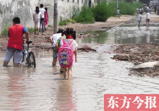 8月27日，郑州市西岗村小学周围道路被雨水淹没，上学的孩子只得涉水穿行