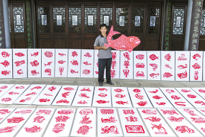 图为谢才华和他的剪纸作品。