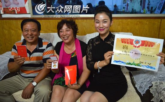 王超的父母和姐姐向大众网记者展示王超获得的荣誉。（记者 王宗阳 摄）