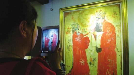 画家钱流在上海的画展现场，一位观众正在拍照。