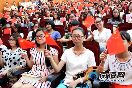 海南大学学生一边挥舞国旗,一边看纪念大会电视直播(南海网记者陈望摄)