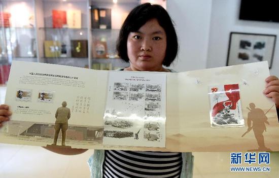 9月3日，郑州市民展示刚刚买到的《中国人民抗日战争暨世界反法西斯战争胜利七十周》纪念邮票。