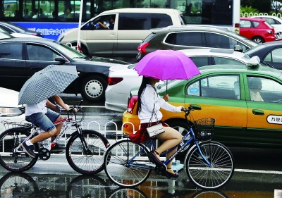 今天上午，降雨还在继续，路上有不少人都得打着雨伞骑行   摄/记者 曹博远