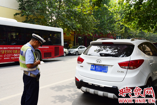 交警接到群众举报后到达现场，对违章停放的现代车拍照，并贴上罚单