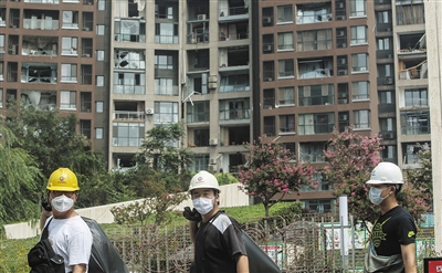 8月14日，天津滨海新区，人们走过被爆炸波及的居民楼。新京报记者 彭子洋 摄
