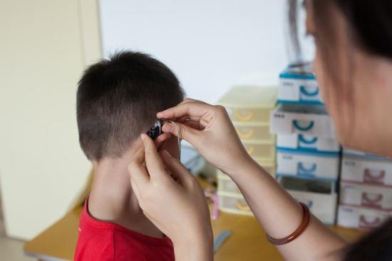 彭晓雯为午休后的小朋友佩戴助听设备(9月7日摄)。