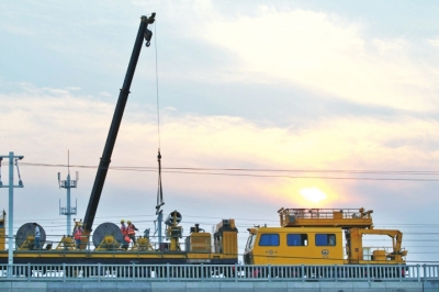 放线车在轨道上施工，工人们傍晚一直工作到黎明。