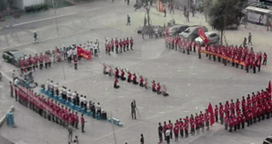 活动中多名身穿红色衣服、黑色裤子的人员跪在地上