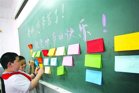 为庆祝教师节来临，同学们在教室布置节日板报。