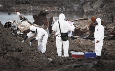 9月8日，天津港爆炸核心区留下的大坑边，三名身穿防化服的工作人员正在对土壤进行取样。新京报记者 尹亚飞 摄