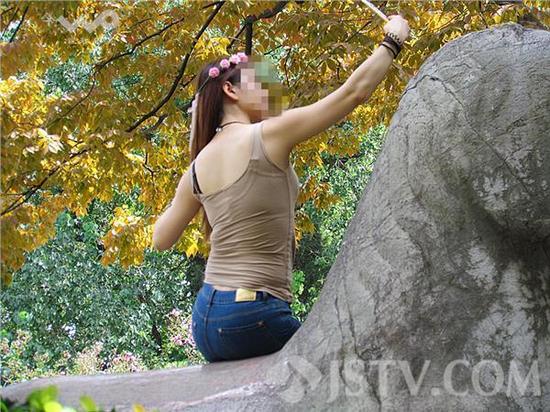 女子爬上石兽玩自拍，姿势不停变换。