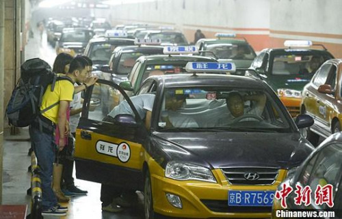 资料图：市民在北京西客站出租车候车点准备乘车。