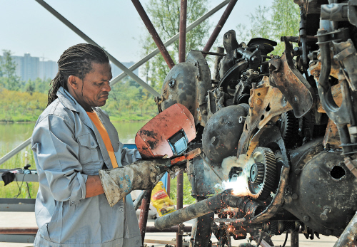 昨日上午，在洋湖湿地公园，南非雕塑家威利·贝斯特尔正在用报废的汽车零部件组装成一匹马。长沙晚报记者 邹麟 摄