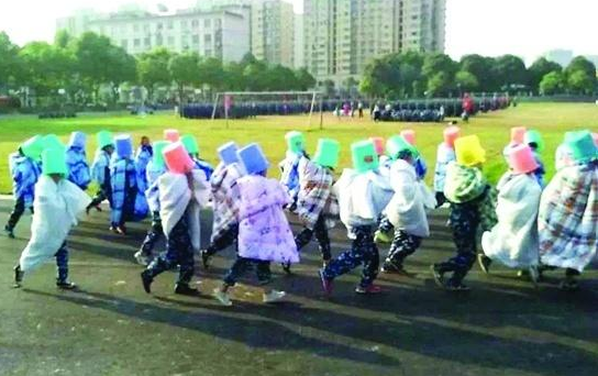 20多名女生裹着棉被躺在操场跑道上,接受太阳的照晒和两千余名同学的围观。(图片来源网络)