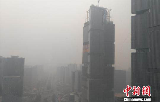 郑州高铁站旁一处双子座建筑隐现在雾霾中。 董飞 摄