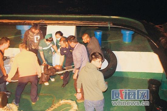 救援人员用担架将突发疾病渔民抬下拖轮。