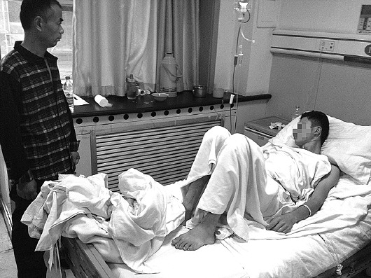 小吴的父亲看着躺在病床上的小吴。