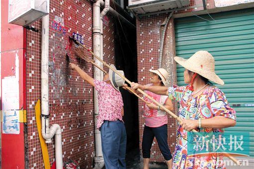 ■白云区嘉禾街望岗经济联社清理“牛皮癣”专业队队员在清理墙上粘贴的小广告。　杨凯/摄