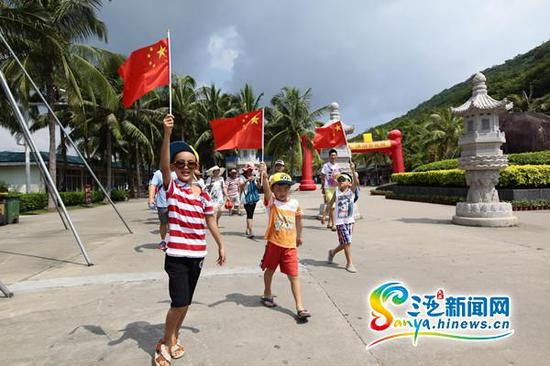 小朋友拿着五星红旗在三亚南山景区游玩。(通讯员陈文武摄)