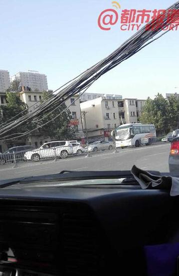郑州线缆刮落致拥堵 小伙单臂举起让车辆通行