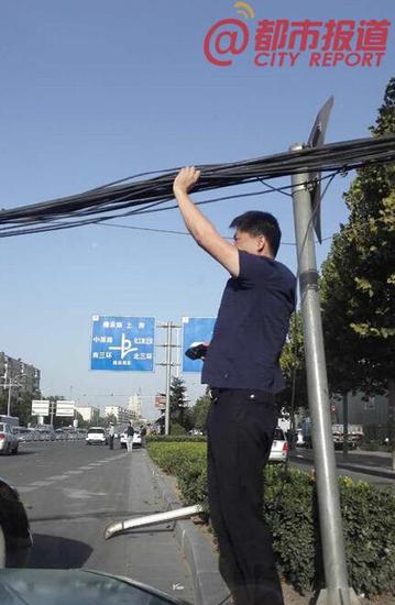 郑州线缆刮落致拥堵 小伙单臂举起让车辆通行