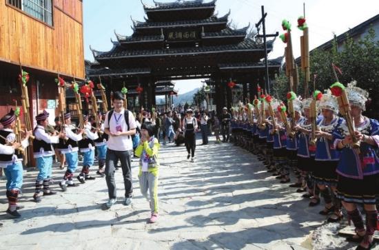 10月2日，通道侗族自治县坪坦乡侗寨的姑娘小伙们身着盛装，吹起芦笙，唱着侗歌，迎接游客进寨。图/通讯员刘强