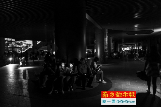 昨日傍晚,受停电影响的广州塔下,市民在黑暗中看手机。南都记者 梁炜培 摄