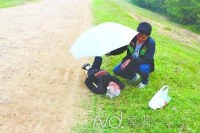 5日，谢波为摔倒的老人撑伞。郑安民 摄