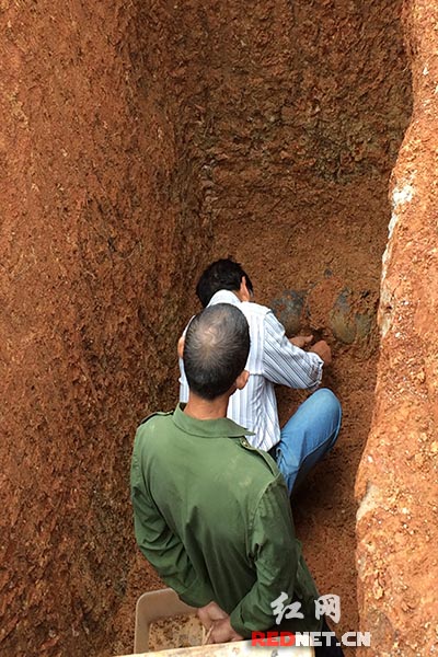 文物保护人员正在对新发现的三件文物上的泥土进行清理。