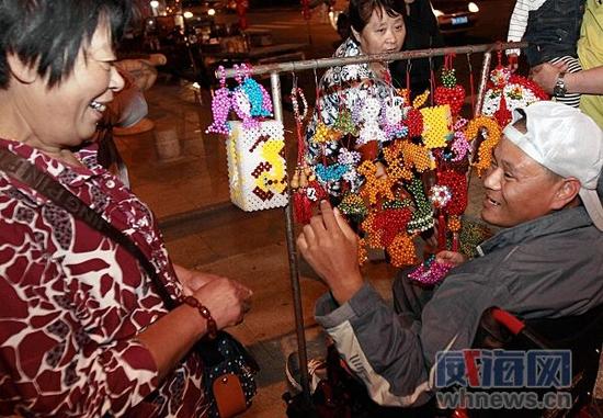 一位大媽的手串鏈繩斷了,張亞亮免費幫她串好。