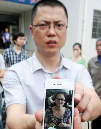 案发后，廖冲舟举着妻子生前的照片。