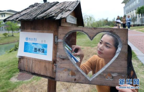 10月13日，桂林医学院的一名大学生打开“鸟巢图书馆”借书。