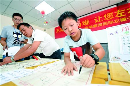 启发孩子均衡使用左右手是改变左手写汉字别扭的一个好方法。图为8月13日,安徽合肥的一小朋友在参加“左手写字”才艺秀。