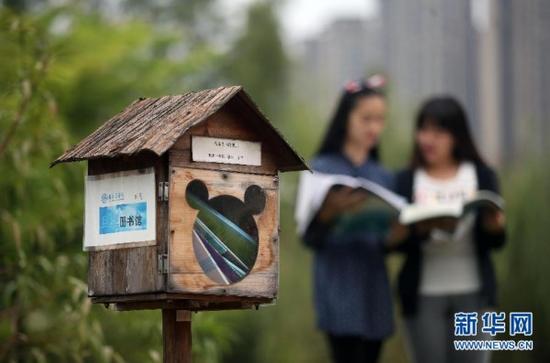 10月13日，桂林医学院的两名大学生在“鸟巢图书馆”旁看书。