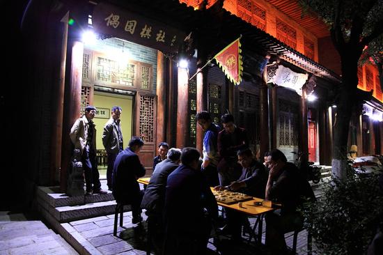 夜色下青州古城街边的市民,在较量着棋术