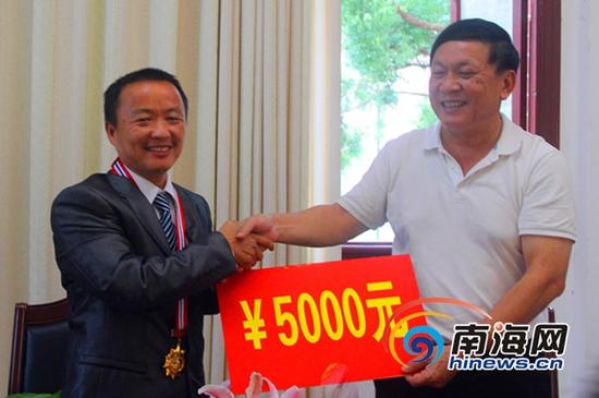 五指山市委副书记、政法委书记李会明代表市委市政府奖励文兵5000元(五指山市委宣传部供图)