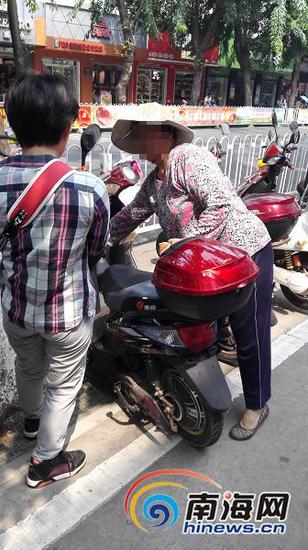 在解放西路一处电动车停放处,一位妇女正在给停车市民发存车卡。