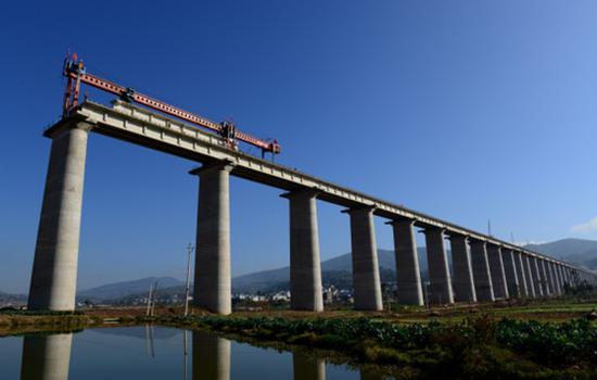 目前泛亚铁路西线云南境内段建设正全面加速推进。图为施工人员在其中一特大桥上进行架梁。