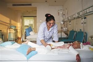 昨日，北京304医院，轩轩妈妈在病床前帮他翻身。一个月前，轩轩掉入滚烫粥锅，造成面积75%烫伤。记者 周岗峰 摄