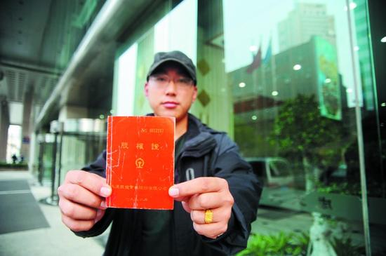 小任拿着父亲留下的股权证,上面写着任力当年认购了1000股股份。半岛晨报、海力网见习摄影记者刘美行