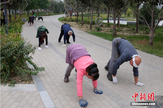 2015年10月22日，河南郑州，商城遗址公园内，一群人爬行锻炼的人：他们戴着手套，四肢着地，弯腰弓背，在地上横爬、竖爬，并不时做出撇胳膊、蹬腿的动作。河南省中医院治未病中心副主任医师吕沛宛吕大夫说，爬行健身起源于华佗的“五禽戏”，是通过模仿动物的爬行 动作来达到健身目的。另外，爬行是全 身性协调活动，使一些平时使用较少的肌肉得到锻炼，可强化全身的肌肉、韧带、骨骼等。图片来源：视觉中国
