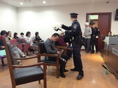 进入法庭后，法警为被告人摘下头盔。京华时报记者 张思佳 摄